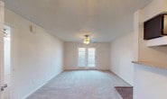 Located at 9209 Saddlehorn Dr in Fort Worth, TX, this single-floor unit offers a practical and comfortable layout throughout. The galley-style kitchen is efficiently designed with dark cabinetry lining both walls, providing ample upper and lower storage. Granite-look countertops, a double basin sink, white appliances including a range and refrigerator, and wood-look flooring complete the kitchen's functional aesthetic. A textured ceiling runs throughout the unit, adding a consistent architectural detail across all rooms. The living area is carpeted and well-lit, featuring a ceiling fan and a charming set of French doors that allow natural light to filter in and offer outdoor access. A secondary living or dining space flows naturally from the entry, also carpeted and illuminated by a ceiling fan, with direct sightlines to the kitchen. The bedroom is a comfortable, well-proportioned room with soft carpeting, a ceiling fan, and a window that brings in natural light. The bathroom features matching dark cabinetry, granite-look countertops, a large vanity mirror with overhead storage, and wood-look flooring that ties back to the kitchen. Overall, the unit presents a cohesive, neutral palette with consistent finishes that create a clean and move-in-ready environment.