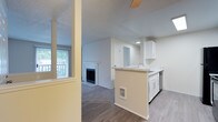 This single-floor residence offers a well-planned layout that balances functionality and comfort. The open-concept design connects the kitchen and living areas seamlessly, creating a cohesive flow throughout the main living space. The kitchen is equipped with crisp white cabinetry, marble-style countertops, a double stainless steel sink, and black appliances including a refrigerator, range, built-in microwave, and dishwasher. Light wood-style flooring runs through the kitchen and entry areas, while plush carpeting extends into the living and bedroom spaces.

The living room is a standout area, centered around a classic tile-surround fireplace with a white mantel. A sliding glass door fills the room with natural light and provides access to an outdoor balcony. A ceiling fan adds both style and function overhead.

The bedrooms are carpeted and offer a calm, neutral palette, with at least one featuring a closet with built-in shelving. A textured ceiling is consistent throughout the home, adding subtle architectural character.

The bathroom is finished with a marble-style countertop vanity, a tub/shower combo with tiled surround, and chrome fixtures. Overall, the space presents a clean, move-in-ready environment with thoughtful details throughout.