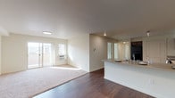 Located at 2555 Bella Colla Lane in Richland, Washington, this single-floor unit offers a thoughtfully designed open-concept layout. The living area is bright and welcoming, featuring rich hardwood-style flooring that transitions seamlessly into plush carpeting, large sliding glass doors leading to a private balcony, and recessed lighting overhead. A peninsula-style kitchen overlooks the living space and is outfitted with warm wood cabinetry, generous counter space, black appliances including a gas range and built-in microwave, and a track lighting fixture that illuminates the workspace. The two bedrooms are carpeted and filled with natural light from wide windows offering exterior views. Each room includes a ceiling fan and closet space, with one bedroom featuring a walk-in closet. A versatile bonus room with hardwood-style flooring connects to the main hallway and is well-suited for use as a home office or den. The bathroom is clean and functional, featuring hardwood-style flooring, a vanity with dark wood cabinetry, and a shower-tub combination. Additional storage is accessible via a coat closet near the entry. The unit's neutral color palette and consistent finishes throughout create a cohesive and comfortable living environment.