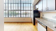 Unit 302 at 101 E Sixth St is a one-bedroom, one-bathroom urban loft on the third floor in the heart of downtown Winston-Salem, NC. The space showcases a striking industrial aesthetic, anchored by warm hardwood floors that run throughout and soaring floor-to-ceiling factory-style windows that flood the interior with natural light and offer expansive city views of the surrounding downtown skyline.

The open kitchen is well-appointed with rich dark wood cabinetry, granite countertops, a stainless steel refrigerator, electric range, built-in microwave, and dishwasher — providing both style and functionality. The kitchen flows naturally into the main living area, making the layout feel open and cohesive.

The generously sized primary bedroom features the same warm hardwood flooring and benefits from two large closets with built-in shelving and hanging rods, offering ample storage. The high ceilings reinforce the loft character throughout the unit.

The bathroom is clean and efficiently designed, featuring large-format tile flooring, a combined tub and shower, a dark wood vanity with granite countertop, and recessed lighting for a polished finish.

Overall, this unit delivers a compelling blend of industrial charm and modern finishes in a compact, well-organized downtown loft setting.