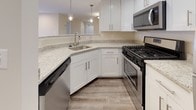 Located at 2411 Little Current Dr in Herndon, Virginia, this single-floor residence offers a well-designed layout with a clean, contemporary aesthetic. The open-concept kitchen is a standout feature, showcasing white shaker cabinetry, speckled granite countertops, and a full suite of stainless steel appliances including a gas range, built-in microwave, dishwasher, and refrigerator. Pendant lighting above the kitchen peninsula adds a modern touch, while wood-look flooring grounds the space with warmth and durability.

The living area is generously proportioned, with plush neutral carpeting, recessed lighting, and a large sliding glass door that allows abundant natural light to fill the room. The bedrooms continue the carpet flooring theme and are each equipped with ceiling fans and sizable windows fitted with blinds, offering pleasant outdoor views and ample brightness. The bathrooms feature wood-look tile flooring, white cabinetry, and full tub-shower combinations with clean, simple fixtures. The overall color palette throughout the residence is light and neutral, creating a bright, airy ambiance. The thoughtful floor plan provides a comfortable and functional living environment in the heart of Herndon.