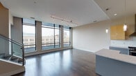 Located in the heart of downtown Grand Rapids, this sophisticated two-floor residence at 47 Commerce Ave SW delivers a refined urban living experience. The open-concept main living area is anchored by expansive floor-to-ceiling windows that flood the space with natural light and frame striking panoramic views of the city skyline. Rich dark hardwood flooring extends throughout the main living areas, complementing the clean, contemporary aesthetic.

The chef's kitchen is a standout feature, outfitted with stainless steel appliances, a gas range, a subway tile backsplash, sleek two-tone cabinetry combining high-gloss lower units with warm wood upper cabinets, and a generous island with stone countertops. Pendant lighting adds an elegant finishing touch overhead.

The bedrooms are bright and airy, each benefiting from large windows with city views. Striped carpeting adds warmth and texture to the sleeping quarters. A spacious walk-in closet with a full built-in organization system provides ample storage. The bathrooms are thoughtfully appointed, featuring marble-topped wood vanities, decorative lighting fixtures, and a glass-enclosed walk-in shower. A second bathroom offers a refined vanity with a stone countertop. Track lighting throughout the home ensures flexible, functional illumination in every room.