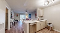 Located in Orlando, FL, this single-floor, 3-bedroom, 2-bathroom unit offers a thoughtfully designed open-concept layout. The kitchen and living room flow seamlessly together, with the kitchen featuring white cabinetry, quartz countertops, stainless steel appliances including a gas range, dishwasher, and refrigerator, plus a peninsula that doubles as a breakfast bar. The adjoining living area is bright and spacious, with wood-style flooring underfoot, a ceiling fan overhead, and large sliding glass doors that open to a private outdoor patio, filling the space with natural light. The primary bedroom is a comfortable retreat with a ceiling fan, natural light from a window with blinds, and direct closet access. Additional bedrooms also feature ceiling fans and open closets with built-in shelving. A dedicated walk-in style closet provides extra storage. Both bathrooms are finished with wood-style flooring, white vanities with quartz countertops, and one includes a full tub-shower combination. A central hallway connects all rooms efficiently. Throughout the unit, neutral tones and consistent flooring create a clean, cohesive aesthetic suited for modern living.
