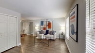 Located at 5618 Eunice Drive in Henrico, Virginia, this single-floor residence offers a thoughtfully designed layout with two bedrooms, two bathrooms, a living room, kitchen, hallway, and closet. The entryway features durable hardwood-style flooring that continues into the living room, where a bright window allows natural light to fill the space, creating an open and welcoming ambiance. The kitchen is well-equipped with stainless steel appliances, including a gas range, over-the-range microwave, refrigerator, and dishwasher, complemented by white shaker-style cabinetry and dark granite-style countertops over light wood-look flooring. The spacious primary bedroom is a standout feature, showcasing a bold orange accent wall, plush carpeting, and a large window with outdoor views. The second bedroom also offers carpet flooring, a window with greenery views, and a built-in corner shelf, alongside a closet for ample storage. The two bathrooms are clean and functional — one features a tiled shower-tub combo, while the other offers a walk-in shower with hardwood-style flooring. Neutral gray tones throughout the home create a cohesive, modern aesthetic.