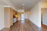 Located at 118 Broadway E in Seattle's vibrant Capitol Hill neighborhood, this well-appointed one-bedroom, one-bathroom unit offers a thoughtfully designed single-floor layout. The open-concept living, dining, and kitchen area forms the heart of the home, bathed in natural light from large floor-to-ceiling windows that frame views of the surrounding cityscape. Wide-plank hardwood-style flooring flows seamlessly throughout, lending a cohesive and modern feel.

The kitchen is outfitted with flat-front light wood cabinetry, a dark tile backsplash, and a full suite of stainless steel appliances including a French door refrigerator, range, microwave, and dishwasher. A hallway connects the main living area to the private bedroom, which features a corner window configuration that draws in ample sunlight and urban views. Two closets provide generous storage, including a walk-in closet with built-in wire shelving systems.

A versatile den offers additional flexible space, while a dedicated in-unit laundry area houses a stacked full-size washer and dryer. The bathroom is accessed via a well-lit hallway with warm wood vanity cabinetry. Clean white walls, recessed lighting, and a modern, minimalist aesthetic define the overall ambiance of this contemporary urban residence.