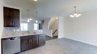 Located at 199 Cedar Park Boulevard in Northampton County, Pennsylvania, this multi-level home spans three floors and offers a well-designed layout with modern finishes throughout. The open-concept main level seamlessly connects the kitchen and living areas, creating a spacious and functional living environment. The kitchen is appointed with rich, dark cabinetry, granite or stone-look countertops, and an undermount sink, complemented by pendant lighting that adds a contemporary touch. Large tile flooring extends across the main level, providing a clean and cohesive aesthetic. An elegant chandelier illuminates the adjoining dining or living area, enhancing the home's warm ambiance. Natural light filters in through multiple windows, brightening the open layout. A centrally located staircase connects all three levels, featuring clean white railings that contribute to the home's fresh, modern feel. The neutral color palette of soft grays and whites throughout creates a versatile backdrop suited to a variety of interior styles. With its thoughtful design, quality finishes, and multi-story layout, this Northampton County home offers a comfortable and stylish living experience.