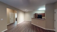 Located at 5555 Long Prairie Trace in Richmond, Texas, this single-floor residence offers a thoughtfully designed open-concept layout that seamlessly connects the living area and kitchen. The living space features rich, dark hardwood-style flooring, warm neutral-toned walls, and a ceiling fan with integrated lighting, creating a comfortable and inviting atmosphere. Track lighting adds a modern touch to the main living area.

The kitchen is well-appointed with rich dark wood cabinetry offering generous storage, stone-tone countertops, and a full suite of black appliances including a refrigerator, range, over-the-range microwave, and dishwasher. A breakfast bar peninsula separates the kitchen from the living area, providing additional counter space and a casual dining option.

The bedrooms are finished with plush carpet flooring and include natural light from windows with blinds, ceiling light fixtures, and ample closet space with built-in shelving and hanging rods. The bathroom is well-equipped, featuring dark wood vanity cabinetry, a sink, toilet, and a tiled shower, all set on durable hardwood-style flooring. The space combines functional design with practical finishes throughout.