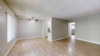 Located at 8828 Highland Ave in Whittier, CA, this single-story 1-bedroom, 1-bathroom unit offers a well-organized and efficiently designed layout. The living room welcomes you with light wood-style flooring, a ceiling fan with integrated lighting, decorative wainscoting along the lower walls, and multiple windows that invite abundant natural light and views of surrounding greenery. A wall-unit AC provides climate control. The living space flows seamlessly toward a hallway leading to the bedroom. The galley-style kitchen is thoughtfully appointed with white shaker cabinetry, dark countertops, a tile backsplash, and a full suite of stainless steel appliances including a range, over-the-range microwave, dishwasher, and refrigerator, all set over light wood-style flooring. The spacious bedroom features plush carpet flooring, a textured ceiling, a window with vertical blinds, and a mirrored sliding-door closet offering generous storage. The bathroom is finished with a wide vanity topped with gray quartz counters, white cabinetry, a large mirror, tile flooring, and a shower/tub combination. Throughout, neutral gray tones and clean white trim create a cohesive, modern aesthetic.