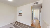 Located at 115 E Broadway in San Gabriel, California, this two-story residence offers a practical and well-organized layout across two floors. The main level provides a generous living area finished with patterned blue-gray carpeting, cream-toned walls, and a sliding glass door that opens to a private balcony with outdoor views — ideal for bringing in natural light and fresh air. A pass-through window connects to an adjacent kitchen area, adding convenience to the open feel of the lower floor.

The upper level houses the bedrooms, connected by a staircase and hallway. The expansive primary bedroom is notably generous in scale, featuring vaulted ceilings that amplify the sense of openness, along with a window that frames views of neighboring rooftops and palm trees. The two additional bedrooms are well-proportioned, each fitted with carpeting, large windows with vertical blinds, and sliding closet doors offering ample storage.

Both bathrooms are clean and functional, featuring tile flooring with a classic diamond pattern, full bathtub-shower combinations, vanities with built-in storage, and bright white finishes throughout. The overall aesthetic of the residence is neutral and move-in ready, with a calm, light palette that suits a variety of living arrangements.