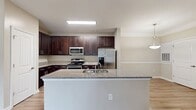 This contemporary townhouse in Wake Forest, NC, offers 1400 square feet of well-designed living space across two floors. The residence features three bedrooms, including a generously sized 210 square foot primary bedroom, and two full bathrooms. The ground floor, spanning 950 square feet, showcases an open-concept layout with a modern kitchen as its centerpiece. Dark wood cabinetry contrasts beautifully with stainless steel appliances and a light-colored island, creating a sleek culinary space. Throughout the home, neutral-toned walls and trim provide a clean backdrop, while wood-look flooring adds warmth and durability. Large windows in the bedrooms and living areas allow for ample natural light, enhancing the sense of space. The bathrooms feature contemporary fixtures, including combination tub-showers with built-in shelving. Practical elements such as ceiling fans and spacious closets with wire shelving systems add functionality. The upper level, comprising 450 square feet, likely houses additional bedrooms or flexible living spaces. This townhouse strikes a balance between style and practicality, offering a turnkey living solution in a desirable location.