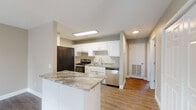 This single-floor unit offers a clean, functional layout with consistent finishes throughout. The open-concept living and kitchen area forms the heart of the space, where a peninsula with granite-look countertops serves as a natural divider. The kitchen is equipped with white shaker-style cabinetry, granite-patterned countertops, stainless steel appliances including a dishwasher and range, and a stainless steel sink — all accented by light wood-style flooring. The living area is generously proportioned, featuring neutral warm-gray walls and durable wood-style flooring that extends throughout the unit.

The two bedrooms each feature ceiling fans with light fixtures, wood-style flooring, windows that bring in natural light, and closet access. The neutral wall tones create a calm and versatile backdrop in each room. Both bathrooms follow a consistent design with wood-style flooring, neutral walls, white vanities, and tub-shower combinations. A separate entry door with a sidelight window provides convenient direct access to one of the bedrooms or a secondary room. Overall, the unit presents a cohesive, move-in-ready aesthetic with practical finishes and a straightforward, easy-to-navigate floor plan.