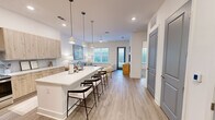 Located at 5102 Station Dr in Birmingham, AL, this thoughtfully designed one-bedroom, one-bathroom residence offers a bright, modern living experience across a single floor. The open-concept layout connects the kitchen, dining, and living areas seamlessly, creating a spacious and cohesive atmosphere. The kitchen is a standout feature, boasting light wood cabinetry, a range hood, stainless steel appliances, a blue tile backsplash, and a generous white quartz island with bar seating illuminated by pendant lighting. Light wood-style flooring flows throughout the main living areas, enhancing the airy feel. The living room is bathed in natural light from large windows and features a ceiling fan, providing views of the surrounding area. The carpeted bedroom is comfortably sized with a ceiling fan, natural light from a window, and direct access to the walk-in closet, which includes built-in shelving and hanging rods. The bathroom features dark cabinetry, a white quartz countertop vanity with an LED-lit mirror, and direct access to the walk-in closet. The overall aesthetic is clean and contemporary, with crisp white walls and modern finishes throughout.