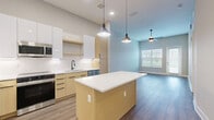 Located at 3175 E Corporate Center Pkwy in Kissimmee, FL, this well-designed one-bedroom, one-bathroom residence offers a thoughtfully planned layout across a single floor. The open-concept living area seamlessly integrates the kitchen, dining, and living spaces into one bright, cohesive environment. The modern kitchen is a standout feature, showcasing light wood and white cabinetry, stainless steel appliances including a refrigerator, range, microwave, and dishwasher, a white quartz countertop island with pendant lighting above, and a subway tile backsplash. Wood-look plank flooring runs consistently throughout the home, adding warmth and continuity. The spacious bedroom features high ceilings, a ceiling fan, natural light from a large window with blinds, and ample room for furnishings. A dedicated closet, in-unit laundry, and utility room provide excellent storage and convenience. Neutral gray and white tones across the walls and trim create a clean, contemporary aesthetic throughout. Exterior views reveal a landscaped, walkable neighborhood setting with easy access to surrounding commercial areas and green spaces.
