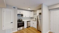 Located at 1500 Champions Pines Lane in Augusta, GA, this one-bedroom, two-bathroom residence offers a well-designed single-floor layout with modern finishes throughout. The kitchen and living room share an open, functional layout anchored by light wood-tone flooring. The kitchen is outfitted with crisp white shaker cabinets, white countertops, a subway tile backsplash, and a full suite of stainless steel appliances including a range, microwave, dishwasher, and refrigerator. A louvered utility closet adds practical storage nearby. The living area is bright and open, featuring recessed lighting and French doors that open to an outdoor patio, inviting natural light and outdoor views into the space. The bedroom is carpeted, offering a cozy retreat, and is served by a dedicated walk-in closet with rod and shelf storage. Both bathrooms are well-appointed; one features a white vanity with a vessel sink, a large mirror with modern light fixtures, and tiled flooring, complementing the clean, contemporary aesthetic found throughout. Neutral wall tones and white trim carry through each room, creating a cohesive and welcoming atmosphere well-suited to a variety of lifestyles.
