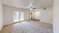 Located on Ninth Street in Lubbock, Texas, this two-bedroom, one-bathroom residence offers a practical and comfortable single-floor layout. The living area is carpeted and features dual ceiling fans with integrated lighting, adding both functionality and airflow throughout the space. French doors in the living room allow natural light to pour in, creating a bright and welcoming atmosphere that opens to the outdoors. The flooring transitions from carpet in the living and bedroom areas to wood-look hard flooring in the kitchen and bathroom. The kitchen is equipped with warm-toned wooden cabinetry, a white electric range, a refrigerator, and a ventilation hood, offering ample storage and a functional cooking space. The primary bedroom is generously sized, featuring a ceiling fan, a sliding-door closet, and a window that brings in natural light. The second bedroom is bright and carpeted, also with a window and convenient access to the hallway. The full bathroom is fitted with a clean, white tub and shower combo, complemented by wood-look flooring. A hallway connects the rooms efficiently, contributing to the home's straightforward and accessible flow. Throughout the space, neutral wall tones and textured ceilings maintain a clean, cohesive aesthetic.
