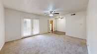 Located on Ninth Street in Lubbock, Texas, this two-bedroom, one-bathroom residence offers a practical and comfortable single-floor layout. The living area is carpeted and features dual ceiling fans with integrated lighting, adding both functionality and airflow throughout the space. French doors in the living room allow natural light to pour in, creating a bright and welcoming atmosphere that opens to the outdoors. The flooring transitions from carpet in the living and bedroom areas to wood-look hard flooring in the kitchen and bathroom. The kitchen is equipped with warm-toned wooden cabinetry, a white electric range, a refrigerator, and a ventilation hood, offering ample storage and a functional cooking space. The primary bedroom is generously sized, featuring a ceiling fan, a sliding-door closet, and a window that brings in natural light. The second bedroom is bright and carpeted, also with a window and convenient access to the hallway. The full bathroom is fitted with a clean, white tub and shower combo, complemented by wood-look flooring. A hallway connects the rooms efficiently, contributing to the home's straightforward and accessible flow. Throughout the space, neutral wall tones and textured ceilings maintain a clean, cohesive aesthetic.