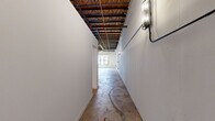 Located in the heart of downtown Atlanta at 210 Pryor St SW, this urban loft delivers a striking industrial aesthetic across a single thoughtfully laid-out floor. The open-plan living and sleeping areas are defined by dramatic exposed steel trusses, raw wood decking overhead, and visible ductwork and conduit — all hallmarks of authentic loft-style architecture. Polished concrete floors run throughout the main living spaces, adding to the raw, warehouse-inspired character while remaining easy to maintain.

The kitchen is well-appointed with contemporary gray wood-grain cabinetry, light quartz countertops, a white subway tile backsplash, and a full suite of stainless steel appliances including a range, refrigerator, and dishwasher. A window in the main living area allows natural light to filter in, offering views of the surrounding Atlanta cityscape.

Both bathrooms feature large-format tile flooring, modern wood-grain vanities with dark countertops, and clean white subway tile detailing. One bathroom includes an open walk-in shower with chrome fixtures. A dedicated closet and hallway provide additional storage and functional flow throughout the unit. The overall ambiance balances rugged industrial character with modern residential finishes, making this a distinctive urban living space.