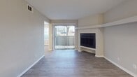 Located at 1920 W Tarrant Rd in Grand Prairie, Texas, this single-floor residence offers a thoughtfully designed layout with a clean, modern aesthetic throughout. The galley-style kitchen is outfitted with white shaker cabinetry, granite-look countertops, a stainless steel sink, and black appliances including a gas range, microwave, and refrigerator — all set above durable wood-look luxury vinyl plank flooring that continues throughout the home. The living area serves as the focal point of the space, featuring a tiled fireplace with a built-in mantle shelf and a sliding glass door that allows natural light to fill the room and provides direct outdoor access. The bedroom areas are generously sized, with large windows offering exterior views, and include both walk-in and bi-fold door closets for ample storage. The primary bedroom benefits from direct access to a private bathroom with a vanity and mirror, while a secondary bathroom is conveniently accessible from the hallway. Neutral wall tones, textured ceilings, and consistent flooring create a cohesive and inviting atmosphere throughout. The overall layout, as seen in the 3D model, reflects a practical and comfortable single-level floor plan suited for everyday living.