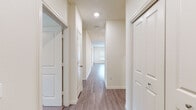 This single-floor residence offers a thoughtfully designed layout that balances open communal spaces with private retreats. The heart of the home is a spacious open-concept kitchen and living area, unified by warm wood-look plank flooring that flows throughout the main spaces. The kitchen is well-equipped with stainless steel appliances, including a refrigerator, range, microwave, and dishwasher. Crisp white shaker-style cabinetry pairs elegantly with dark granite countertops, while a tile backsplash adds a refined touch. A central island provides additional prep space and casual seating. Recessed and pendant lighting complete the kitchen's polished look. The living area is generously proportioned, benefiting from natural light through multiple windows. A hallway connects the main living spaces to the private areas of the home, where carpeted bedrooms offer a comfortable, quiet atmosphere. Each bedroom features a ceiling fan and closet with built-in shelving for ample storage. The bathrooms are finished with neutral tile flooring, white cabinetry, dark granite vanity tops, and tub-shower combinations with tile surrounds. Clean, neutral wall tones and consistent design choices throughout create a cohesive, move-in-ready environment.
