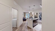 Located at 1100 South Boulevard in Charlotte's vibrant South End neighborhood, this well-appointed one-bedroom, one-bathroom residence offers a thoughtfully designed open-concept layout. Wood-look flooring flows throughout the main living areas, anchoring a seamless combination of dining, kitchen, and living space filled with natural light from large windows.

The modern kitchen is a standout feature, boasting dark espresso cabinetry extending to the ceiling, stainless steel appliances including a refrigerator, electric range, and microwave, and a central island with a granite-style countertop and bar seating for two — ideal for casual dining or entertaining. Pendant lighting and track lighting illuminate the space with style.

The open living area provides comfortable space for relaxing and dining, with access to natural light and an inviting, airy atmosphere. The bedroom offers plush carpeting, a ceiling fan, and a window with exterior views, creating a calm and restful retreat. Three closets throughout the unit offer generous storage.

The bathroom features dark-framed cabinetry, a large vanity mirror, granite-style countertops, and wood-look tile flooring. A dedicated laundry room with a full-size washer hookup and overhead shelving adds everyday convenience. A utility room rounds out the functional offerings of this well-equipped residence.