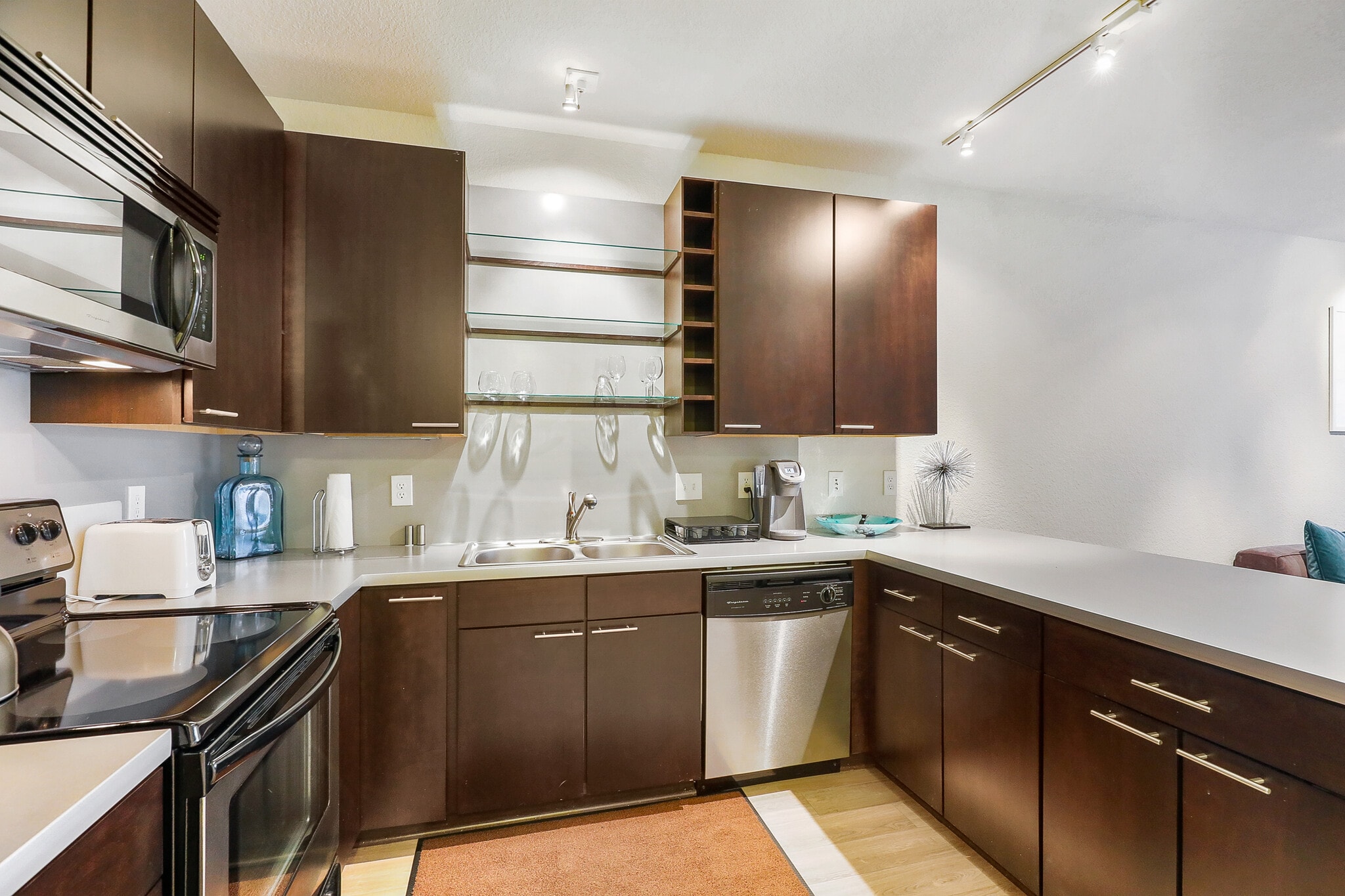 Modern kitchen with dark wood cabinets, stainless steel appliances, and a large countertop.