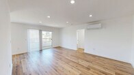 Located at 1185 Myra Ave in the heart of Los Angeles, CA, this thoughtfully designed 2-bedroom, 2-bathroom unit offers a clean, modern aesthetic throughout its well-appointed single-floor layout. Warm-toned light wood flooring flows seamlessly through every room, complementing the crisp white walls and creating a bright, cohesive atmosphere.

The open living and dining area is bathed in natural light, anchored by recessed lighting and a wall-mounted split air conditioning unit. Sliding glass doors with vertical blinds open to a private balcony, providing outdoor access and additional natural light. The galley-style kitchen is a standout feature, equipped with white shaker cabinets, quartz countertops, a subway tile backsplash, stainless steel appliances including a gas range and dishwasher, and matte black hardware throughout.

Both bedrooms are generously proportioned with large windows, recessed or flush-mount lighting, and ample closet space. The primary bedroom includes its own split AC unit and a dedicated closet. Three total closets provide excellent storage across the unit.

The two bathrooms are finished with striking hexagonal slate-gray floor tiles, white subway tile walls, white vanities with undermount sinks, and matte black fixtures. One bathroom features a glass-enclosed walk-in shower, while the other offers a full bathtub-shower combination.
