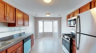 This single-floor residence at Crown Court offers a clean, functional layout designed for comfortable everyday living. The kitchen is a standout feature, showcasing rich warm-toned wood cabinetry that lines both sides of the space, paired with dark granite-style countertops that provide an attractive contrast. Fully equipped with stainless steel appliances — including a gas range, built-in microwave, and dishwasher — the kitchen is designed to meet all culinary needs. Light tile flooring runs throughout, lending a bright and cohesive feel to the space. At the far end of the kitchen, a charming bay window nook floods the area with natural light and offers a welcoming spot for a dining set or breakfast table. The neutral gray-toned walls serve as a versatile backdrop, complementing the warm wood tones of the cabinetry and creating a balanced, inviting atmosphere. The overall design is practical yet aesthetically pleasing, with thoughtful details that make everyday living both convenient and comfortable. This residence presents a well-maintained, move-in-ready space suited for a range of lifestyles.
