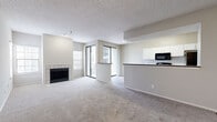 This single-floor, 2-bedroom, 2-bathroom residence offers a functional and comfortable layout designed for everyday living. The open living and dining area is finished with plush neutral carpeting and features a tiled fireplace as a central focal point. Large sliding glass doors lead to a private balcony, flooding the space with natural light and providing outdoor views. A second window with blinds adds further brightness to the living area.

The galley-style kitchen is equipped with white cabinetry featuring modern bar-pull hardware, dark granite-style countertops, black appliances including a range and refrigerator, and a classic white subway tile backsplash. Wood-look flooring runs throughout the kitchen, adding warmth and easy maintenance.

Both bedrooms are carpeted and offer dedicated closet space, with the primary bedroom benefiting from its own walk-in closet with built-in shelving and hanging rods, as well as a private en-suite bathroom. The bathrooms feature wood-look flooring, white vanity cabinetry with dark countertops, and a tiled soaking tub with a window for natural light. Additional hallways and closets throughout the home provide ample storage. The neutral color palette and textured ceilings create a clean, cohesive aesthetic throughout.