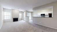 This single-floor, 2-bedroom, 2-bathroom residence offers a functional and comfortable layout designed for everyday living. The open living and dining area is finished with plush neutral carpeting and features a tiled fireplace as a central focal point. Large sliding glass doors lead to a private balcony, flooding the space with natural light and providing outdoor views. A second window with blinds adds further brightness to the living area.

The galley-style kitchen is equipped with white cabinetry featuring modern bar-pull hardware, dark granite-style countertops, black appliances including a range and refrigerator, and a classic white subway tile backsplash. Wood-look flooring runs throughout the kitchen, adding warmth and easy maintenance.

Both bedrooms are carpeted and offer dedicated closet space, with the primary bedroom benefiting from its own walk-in closet with built-in shelving and hanging rods, as well as a private en-suite bathroom. The bathrooms feature wood-look flooring, white vanity cabinetry with dark countertops, and a tiled soaking tub with a window for natural light. Additional hallways and closets throughout the home provide ample storage. The neutral color palette and textured ceilings create a clean, cohesive aesthetic throughout.