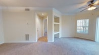 Located at 909 Penn Waller Rd in Savannah, Georgia, this single-floor residence offers a well-designed layout with a clean, neutral aesthetic throughout. The living area features plush carpeting, crown molding, and built-in shelving that adds both character and storage functionality. A pass-through counter connects the living space to the kitchen, enhancing the open feel of the common areas.

The kitchen is outfitted with white cabinetry, dark granite-style countertops, stainless steel appliances including a refrigerator, range, microwave, and dishwasher, and warm hardwood-style flooring that adds a welcoming contrast to the bright cabinetry.

Multiple bedrooms are carpeted and feature ceiling fans with lighting, natural light from windows with outdoor views of surrounding greenery, and generous closet space — including a walk-in closet in one of the bedrooms. One bedroom also benefits from crown molding and a sliding glass door leading to an outdoor space.

The two full bathrooms are well-appointed with white vanity cabinetry, granite-style countertops, large mirrors with overhead lighting, tub/shower combinations, and hardwood-style flooring. Together, the rooms present a cohesive, comfortable living environment with practical finishes throughout.