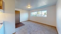 Located at 1359 Pohl Rd in Mankato, Minnesota, this single-floor unit offers a practical and straightforward layout designed for comfortable everyday living. The entry foyer features durable wood-look flooring that transitions into plush carpeting throughout the main living areas, providing a warm and inviting feel underfoot.

The living room is a generous, open space bathed in natural light through a wide bank of windows that offer views of the surrounding neighborhood. A textured ceiling and neutral white walls create a clean, versatile backdrop throughout. An adjacent dining or secondary living area connects seamlessly to the kitchen, enhancing the flow of the space.

The kitchen is well-appointed with warm oak cabinetry offering ample storage, light-toned countertops, and white appliances including an electric range, dishwasher, and refrigerator. Wood-look flooring in this area adds a practical, easy-to-maintain surface.

The bedroom is a comfortably sized, carpeted room featuring a broad closet with built-in shelving and a window that allows natural light to fill the space. An additional room, also carpeted and naturally lit, provides flexible use as a second bedroom or office.

The bathroom includes a single vanity with an oak-framed medicine cabinet, a combined tub and shower unit, and wood-look flooring, maintaining the consistent, functional aesthetic found throughout the unit.