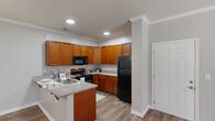 Located at 192 Ballentine Crossing Ln in Irmo, SC, this well-appointed two-bedroom, two-bathroom residence offers a thoughtfully designed single-level layout. The kitchen is a standout feature, showcasing warm honey-toned wood cabinetry, granite-style countertops, a double stainless steel sink, and black appliances including an electric range, built-in microwave, and refrigerator. Crown molding and recessed lighting add a polished finish to the space. The kitchen flows naturally into the dining area, creating an open and functional layout ideal for everyday living.

The living area is bright and airy, benefiting from natural light through glass patio doors that provide outdoor access and views of surrounding greenery. Durable hardwood-style flooring runs throughout the main living spaces, while plush carpeting adds comfort to the bedrooms. The primary bedroom is generously sized and includes a walk-in closet with wire shelving for ample storage.

Both bathrooms are finished with rich wood vanities, large mirrors, and tub-shower combinations with hardwood-style flooring. A dedicated closet provides additional storage. Neutral wall tones and consistent crown molding throughout create a cohesive and inviting atmosphere across the entire residence.