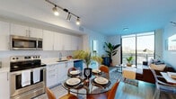 Located at 1569 NW 17th Ave in Miami, FL, this well-appointed 2-bedroom, 2-bathroom unit offers a thoughtfully designed single-floor layout with modern finishes throughout. The open-concept kitchen and living area serves as the heart of the unit, featuring a sleek kitchen with white cabinetry, stainless steel appliances including a refrigerator, range, microwave, and dishwasher, and light wood-look flooring that extends throughout the space. Track lighting overhead adds a contemporary touch to the kitchen and dining area. The living room is bathed in natural light from floor-to-ceiling sliding glass doors that open to a private balcony, offering views of the surrounding Miami skyline and a glimpse of a pool area below. The two bedrooms are accessible via clean, bright hallways with louvered closet doors, providing ample storage. The primary bedroom offers a calm, minimalist atmosphere with warm wood flooring and generous wall space. Both bathrooms are finished with white vanities, wood-look flooring, and a clean, modern aesthetic. Throughout the unit, crisp white walls, neutral tones, and abundant natural light create a bright and airy ambiance well-suited to Miami's sunny climate.