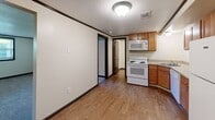 Located at 1717 Kuntz Rd in Erie, Pennsylvania, this two-bedroom, one-bathroom single-floor home offers a practical and efficiently designed layout. The interior features a clear distinction between living and functional spaces, with warm wood-look flooring running through the kitchen and connecting hallway areas, while soft carpeting covers both bedrooms.

The kitchen is well-equipped with warm honey-toned wood cabinetry, granite-look countertops, and a full suite of white appliances including an electric range with coil burners, a built-in microwave, dishwasher, and refrigerator. A stainless steel sink completes the workspace, and the open sightline into the hallway gives the area an airy, connected feel.

Both bedrooms are generously proportioned, with the primary bedroom offering a notably spacious footprint. Each room features neutral cream-colored walls with dark contrasting trim, soft carpet flooring, and windows that allow natural light and outdoor views. A programmable thermostat is present in the primary bedroom for individual climate control.

The bathroom is clean and functional, featuring a full tub and shower combination with built-in shelving, a white vanity with sink, and wood-look flooring. Textured ceilings with flush-mount lighting are consistent throughout the home, contributing to a cohesive and tidy aesthetic.