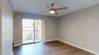 This single-story unit is thoughtfully laid out, offering a functional and comfortable living environment. The main living area features warm wood-style flooring and is centered around a ceiling fan with integrated lighting. A sliding glass door opens to a private balcony, allowing natural light to fill the room while providing views of the surrounding greenery.

The kitchen is well-appointed with white shaker-style cabinetry, granite-look countertops, and black appliances including an electric range, dishwasher, and a range hood. A double-basin sink sits beneath a window, and the wood-style flooring continues throughout this space, contributing to a cohesive aesthetic.

The bedrooms vary in finish, with one room showcasing plush carpeting and a window that frames outdoor views, while another features the same wood-style flooring found in the main living areas, complete with a ceiling fan. Both rooms include louvered bifold closet doors offering ample storage. A built-in niche adds a unique architectural detail between rooms.

The bathrooms are clean and functional, each featuring a tiled tub-and-shower combination, white vanity, and wood-style flooring. Textured walls and popcorn ceilings are consistent throughout, contributing to the unit's established character.