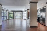 Located at 100 Drexel Point in Dunwoody, GA, this single-floor residence offers a well-designed, open-concept layout with consistent hardwood flooring throughout the main living areas. The gourmet kitchen is a standout feature, showcasing rich dark espresso cabinetry, dark granite countertops with subtle green and gold flecks, a glass tile mosaic backsplash, and a full suite of stainless steel appliances including a gas range, over-the-range microwave, and French door refrigerator. A curved kitchen island with a stainless steel sink and pendant lighting adds both functionality and visual interest, seamlessly connecting the kitchen to the living area. The spacious living room is defined by a tray ceiling with elegant crown molding and large floor-to-ceiling windows that flood the space with natural light and offer pleasant outdoor views of surrounding greenery. The bedrooms feature hardwood floors and generously sized windows. The bathrooms are finished with light tile flooring, dark vanity cabinetry, granite countertops, and tub-shower combinations; the primary bath additionally includes a separate glass-enclosed shower stall. Throughout, the space balances refined finishes with a clean, neutral palette.