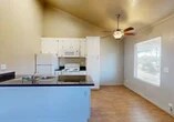 Located at 1011 Rosemarie Ln in Stockton, CA, this one-bedroom, one-bathroom unit offers a efficient and well-appointed single-floor layout. The open-concept kitchen and living area is immediately eye-catching, defined by striking vaulted ceilings that lend a sense of spaciousness well beyond the unit's compact footprint. The kitchen features a peninsula with dark granite countertops, a double stainless steel sink, ample white cabinetry extending to the ceiling, and white appliances including a refrigerator, electric range, and built-in microwave. Wood-look flooring flows throughout the main living area, complemented by a ceiling fan with light fixture and a window that brings in natural light with views of surrounding trees. The bedroom offers comfortable carpeted flooring, crown molding, a window overlooking greenery, and access to a dedicated closet. The bathroom is finished with wood-look flooring, a white vanity with dark granite countertop, and a full shower-tub combination enclosed by sliding glass doors. A hallway connects the main living spaces to the bedroom and bathroom, completing this practical and neatly designed residence.