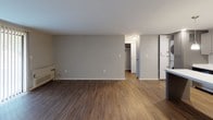 Located at 2505 Quail Ridge Drive in Plainsboro, NJ, this single-floor 1-bedroom, 1-bathroom residence offers a thoughtfully designed layout with modern finishes throughout. The renovated kitchen is a standout feature, showcasing gray shaker-style cabinetry, crisp white quartz countertops, a stainless steel appliance suite including a gas range, built-in microwave, dishwasher, and refrigerator, and a central island with pendant lighting — all set atop warm wood-look flooring. The open-concept design allows the kitchen to flow naturally toward the living area, which features rich hardwood-style flooring, a classic fireplace, and a large sliding glass door with vertical blinds that brings in abundant natural light. The spacious bedroom is finished with plush carpeting, a window overlooking the greenery outside, and a generous closet. A clean hallway connects the main living spaces to the full bathroom, which includes a white vanity with an undermount sink. The neutral color palette, recessed lighting, and consistent flooring choices throughout create a cohesive, move-in-ready environment suited for comfortable everyday living.