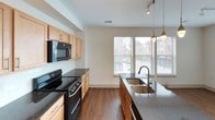This single-floor unit offers a well-designed open-concept layout with consistent hardwood-style flooring throughout the living spaces. The kitchen serves as a central hub, featuring dark granite countertops, light maple cabinetry with a subway tile backsplash, and black appliances including a refrigerator, range, and built-in microwave. A peninsula island with an undermount double sink provides additional workspace and separates the kitchen from the living area. Pendant lighting and track lighting illuminate the space, while multiple windows fitted with blinds allow abundant natural light and views of the surrounding neighborhood.

The living area is generously proportioned, with neutral-toned walls and ample room for varied furniture arrangements. Each bedroom includes hardwood-style flooring, a ceiling fan with integrated lighting, and windows that bring in natural light. The bedrooms offer a calm, neutral aesthetic suited for comfortable everyday living.

The bathrooms are finished with large-format tile flooring, white fixtures, a tub-shower combination, and vanity with countertop sink. Clean lines and neutral tones carry throughout, giving the entire unit a cohesive, contemporary feel.