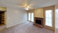 This single-floor residence offers a well-organized layout with comfortable living spaces throughout. The living room serves as the heart of the home, featuring plush carpeting, a ceiling fan with light fixture, a textured ceiling, and a charming brick fireplace framed by a diagonal wood-paneled surround. French doors lead directly to an outdoor patio, filling the room with natural light and providing easy outdoor access.

The galley-style kitchen is efficiently designed with warm wood cabinetry lining both walls, offering generous storage space. It is equipped with a double stainless steel sink, a coil-top range, a black refrigerator, a built-in microwave, and a dishwasher. A pass-through counter connects the kitchen to the living area, enhancing the open feel of the space.

An additional carpeted room features its own ceiling fan, recessed lighting, a textured ceiling, and French doors that open to the outside, making it a versatile space suitable as a bedroom or flex room.

The bathroom is clean and functional, featuring a wood-toned vanity with a white countertop and integrated sink, a large wall mirror, pendant lighting above the vanity, and a full shower-tub combo with white tile surround. Throughout the unit, neutral tones and consistent finishes create a cohesive and practical living environment.
