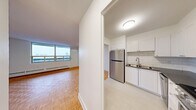 This well-appointed one-bedroom, one-bathroom unit is located at 2233-2235 Hurontario Street in Mississauga, Ontario. The layout is thoughtfully organized across a single floor, offering a comfortable and functional living environment. Warm parquet wood flooring runs throughout the living areas and bedroom, adding a classic character to the space.

The open combined dining and living area is bright and inviting, anchored by large floor-to-ceiling windows that flood the room with natural light and offer expansive views of the surrounding treed landscape. A private balcony extends from the living area, providing an outdoor retreat with scenic views overlooking a natural wooded area.

The kitchen is neatly appointed with white shaker-style cabinetry, a subway tile backsplash, dark countertops, and stainless steel appliances including a full-size refrigerator, electric range, and dishwasher. Light flooring completes the clean, modern aesthetic.

The bedroom is a well-sized retreat featuring parquet flooring, a large sliding-door closet, and a baseboard heating unit. Additional storage is available through multiple closets located throughout the unit. The bathroom is finished with crisp white subway tile surrounding a full soaker tub and shower combination, complemented by a small window for ventilation and natural light.