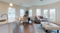 Located at 30 Main in Londonderry, New Hampshire, this thoughtfully designed single-floor residence offers a seamless blend of modern finishes and functional living spaces. The open-concept layout connects the kitchen, dining, and living areas, creating a bright and inviting atmosphere bathed in natural light from an abundance of large windows throughout.

The kitchen is a standout feature, boasting striking granite countertops with dramatic veining, white shaker-style cabinetry, a classic subway tile backsplash, stainless steel appliances, and a generous island with bar seating — ideal for both everyday meals and entertaining.

The living and dining areas share a warm, welcoming ambiance with rich hardwood flooring, vaulted ceiling details, and expansive windows that frame outdoor views and flood the space with daylight. A separate sitting room provides a quieter retreat, also enhanced by large windows and neutral tones.

The bedrooms are comfortably sized and finished with plush carpeting and ample natural light. The primary suite includes access to a well-appointed bathroom featuring light tile flooring, sleek gray cabinetry, and a walk-in closet with built-in shelving. An additional half bathroom is clean and efficiently designed with a white vanity. The overall aesthetic is cohesive, modern, and move-in ready.
