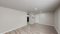 Located at 80 River Chase Dr in Dover, Delaware, this single-floor, three-bedroom, one-bathroom home offers a clean, modern interior with a neutral color palette throughout. The open living area is finished with light wood-look luxury vinyl plank flooring and recessed lighting, creating a bright and welcoming atmosphere. A pass-through window connects the living space to the kitchen, which features white shaker-style cabinetry, a stainless steel sink, solid countertops, and black appliances including a range, built-in microwave, and dishwasher. The primary bedroom is a comfortable size, finished with plush carpeting and a large window that draws in natural light. The two additional bedrooms are also carpeted and include windows with views of the surrounding greenery, providing a quiet and restful setting. The full bathroom is well-appointed with a white vanity, mirror with overhead lighting, and a tub-shower combination. Consistent white panel doors, clean baseboards, and a cohesive neutral tone throughout the home lend it a fresh, move-in-ready feel. The layout is efficient and functional, making excellent use of the available square footage across all rooms.