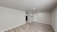 Located at 80 River Chase Dr in Dover, Delaware, this single-floor, three-bedroom, one-bathroom home offers a clean, modern interior with a neutral color palette throughout. The open living area is finished with light wood-look luxury vinyl plank flooring and recessed lighting, creating a bright and welcoming atmosphere. A pass-through window connects the living space to the kitchen, which features white shaker-style cabinetry, a stainless steel sink, solid countertops, and black appliances including a range, built-in microwave, and dishwasher. The primary bedroom is a comfortable size, finished with plush carpeting and a large window that draws in natural light. The two additional bedrooms are also carpeted and include windows with views of the surrounding greenery, providing a quiet and restful setting. The full bathroom is well-appointed with a white vanity, mirror with overhead lighting, and a tub-shower combination. Consistent white panel doors, clean baseboards, and a cohesive neutral tone throughout the home lend it a fresh, move-in-ready feel. The layout is efficient and functional, making excellent use of the available square footage across all rooms.