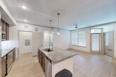 Located at 14919 TC Jester Boulevard in Houston, TX, this single-story 2-bedroom, 2-bathroom home offers a well-designed open-concept layout. The kitchen is a standout feature, showcasing rich dark-wood cabinetry, granite countertops, a subway tile backsplash, and a full suite of stainless steel appliances including a refrigerator, range, and built-in microwave. A central island with a granite surface and integrated sink doubles as a breakfast bar, seamlessly connecting the kitchen to the dining and living areas. Light wood-style flooring runs throughout the main living spaces, enhancing the bright, airy feel created by recessed lighting and modern pendant fixtures. The living area is equipped with a ceiling fan and large windows with blinds that invite natural light. Both bedrooms feature plush carpeting and ceiling fans, with the primary bedroom offering generous proportions and its own en-suite bathroom. The primary bath includes a dual-sink vanity with granite countertops, while the secondary bathroom features a tub-shower combo and matching finishes. Three closets provide ample storage throughout, and a dedicated laundry room with a full-size washer and dryer adds everyday convenience.