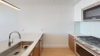 Located in the heart of downtown Los Angeles, this single-floor residence at 427 W 5th St offers a thoughtfully designed layout with clean, modern aesthetics throughout. Light hardwood flooring flows seamlessly across the open living areas, complementing the bright white walls and recessed lighting that give the space an airy, contemporary feel.

The kitchen is a standout feature, showcasing warm wood cabinetry with sleek metal hardware, a striking stone-topped island with an undermount sink and pendant lighting above, and a full suite of stainless steel appliances including a gas range, microwave, and a full-size refrigerator. A subtle teal tile backsplash adds a refined pop of color to the cooking area.

The bedroom is well-proportioned and benefits from natural light, offering generous built-in closet storage with dual sliding doors and organizational shelving systems — a practical and functional detail.

The bathroom is finished to a high standard, featuring large-format tile flooring, a wood vanity with a stone countertop, a backlit mirror, and a combined tub and shower enclosure with glass surround and open shelving. The overall design is cohesive and polished, reflecting a modern urban lifestyle in one of Los Angeles' most vibrant neighborhoods.