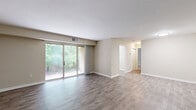 Located at 7105 Fernwood St in Henrico, Virginia, this single-floor, one-bedroom, one-bathroom home offers a generously sized and thoughtfully laid-out living space. The interior is finished with a neutral warm beige color palette throughout, complemented by wood-look hard flooring in the main living areas and plush carpeting in the bedroom. The spacious living room provides an open, airy feel with clean lines and bright, flush-mounted lighting. The updated kitchen is a standout feature, boasting white shaker-style cabinetry, granite-look countertops, a deep basin sink, and black appliances including a gas range, built-in microwave, and full-size refrigerator, all set atop light-toned wood-look flooring. A dedicated laundry area houses a stacked washer and dryer unit for added convenience. The generously sized bedroom features carpet flooring, a large window framing lush, wooded views, and direct access to a walk-in closet with built-in shelving and hanging rods. The full bathroom includes a clean, white tub-shower combination with built-in shelving. A private outdoor area overlooks a verdant, tree-lined backyard, offering a tranquil natural setting.