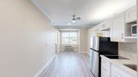 Located in Vancouver, WA, this efficient 2-bedroom, 1-bathroom residence offers a thoughtfully designed layout that maximizes every square foot. The open living, dining, and kitchen area is anchored by light wood-style laminate flooring, neutral warm-toned walls, and elegant crown molding that runs throughout, lending a polished feel to the space. A ceiling fan overhead and a bright window with exterior views add comfort and natural light to the living area.

The kitchen is well-appointed with crisp white shaker cabinetry, marble-veined quartz countertops, a classic tile backsplash, a stainless steel refrigerator, a built-in cooktop, and an over-the-counter microwave — providing solid functionality in a compact footprint.

Both bedrooms carry the same warm, neutral palette and light flooring, each featuring a sliding-door closet with built-in shelving and windows that let in generous natural light with pleasant outdoor views of surrounding greenery.

The full bathroom is designed with accessibility in mind, featuring a roll-in tiled shower with stainless steel grab bars, a handheld showerhead, mosaic tile flooring, and white cabinetry for storage. This residence combines practical, accessible design with clean modern finishes throughout.