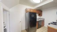 Located at 3511 Briel St in Richmond, Virginia, this two-floor residence offers a clean, functional layout with consistent finishes throughout. The main living area greets occupants with light wood-style flooring and neutral white walls, creating a bright and open atmosphere. A window allows natural light to filter into the space, enhancing its airy feel.

The kitchen is well-appointed with warm medium-toned wood cabinetry extending to the upper walls for generous storage. Black appliances — including a refrigerator, electric range, over-the-range microwave, and dishwasher — complement the light countertops, while the wood-style flooring continues seamlessly underfoot.

Bedrooms feature plush carpeting and double-door closets, offering comfortable and practical living quarters. Ceiling fans in select bedrooms add to the functionality. The bathroom includes a full tub and shower combination with clean white surroundings.

A dedicated laundry area tucked under the staircase accommodates a stacked washer and dryer unit, adding everyday convenience. Additional storage is provided via louvered closet doors nearby. The two-floor layout offers a natural separation of living and private spaces, making this Richmond residence a practical and well-organized home.