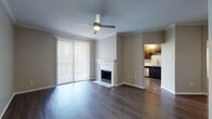 This single-story unit is finished with wood-style flooring that runs consistently throughout all rooms, lending a cohesive and clean aesthetic to the space. The living area serves as the focal point of the unit, featuring crown molding, a ceiling fan with integrated lighting, and a white-mantled fireplace. Large sliding glass doors fitted with vertical blinds allow natural light to flood the room while providing outdoor access. The living area flows directly into the kitchen, which is outfitted with dark espresso cabinetry, light countertops, a subway tile backsplash, and a full suite of stainless steel appliances including a gas range, over-the-range microwave, and refrigerator.

The bedrooms are well-proportioned, each equipped with ceiling fans, ample natural light from large windows with outdoor views of greenery, and access to closets. Crown molding is present in select rooms, adding a refined architectural detail.

The bathroom features dark cabinetry paired with light countertops, a dual-sink vanity, a large mirror, and a tub and shower combination with a curved rod. Wood-style tile flooring ties the bathroom finish seamlessly to the rest of the unit's design.